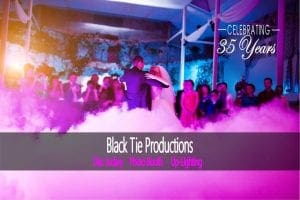 In a vibrant lair bathed in neon pink and blue luminescence, two figures glide across the floor with superhuman grace. Their every move captivates the room as if orchestrated by an unseen force. The name Black Tie Productions blazes above in bold letters, reminiscent of a call to heroism, accompanied by the triumphant declaration: Celebrating 35 Years. A list of powers unfurls beneath—event lighting that transforms any space into a realm of wonder and photo booth rentals that capture epic moments for eternity. :The Event Heroes at Black Tie Productions