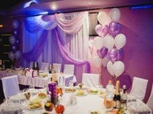 Event Heroes Assemble! Behold a venue transformed by the might of Event Heroes, where majestic purple and white balloons soar against a backdrop of elegant drapes that ripple like capes in the wind. Feast your eyes upon tables overflowing with a heroic array of delicious foods and thirst-quenching drinks. Immortalize your epic journey with our supercharged photo booth rental, crafting memories that will endure through time’s fiercest battles!. :The Event Heroes at Black Tie Productions