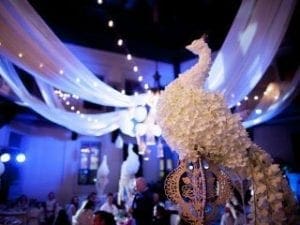 Amidst the grandeur of the wedding reception, a magnificent floral peacock centerpiece took center stage, a true marvel crafted from nature’s finest blooms. Its beauty soared even higher as it was enshrouded in majestic drapes and sparkling string lights that danced like stars across an evening sky. Enter Black Tie Productions, the legendary heroes of ambiance, renowned across Michigan for their unparalleled DJ services. With a masterful touch, they cast their spell of event lighting to transform the atmosphere into an epic tableau fit for loves most triumphant celebration!. :The Event Heroes at Black Tie Productions