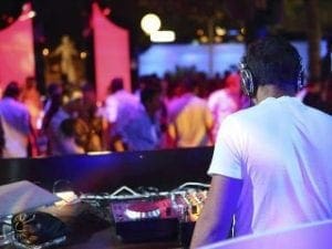 Amidst the vibrant outdoor arena, a sonic savior emerges. Clad in the emblematic gear of Black Tie Productions, this DJ dons his powerful headphones like a crown of rhythm. With every beat drop, he unleashes an electrifying surge that reverberates through the crowd, turning mere onlookers into an energized assembly. His fingertips dance over the controls with unmatched precision, crafting a musical odyssey that transforms the ordinary day into an extraordinary spectacle. In this moment, he is more than a performer; he is a maestro of momentum, igniting souls with unwavering rhythm and sound. :The Event Heroes at Black Tie Productions