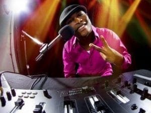 Amidst the dazzling spectacle of a heros arena, where vibrant event lighting dances with colorful stage beams, stands the Sonic Sentinel. Clad in a radiant pink costume and cap, they command the DJ setup with unyielding prowess. With one hand forming the universal sign of peace and victory, their voice booms through the microphone like a benevolent sonic wave. Black Tie Productions orchestrates this electrifying battleground, transforming it into an uplifting haven of sound and light. :The Event Heroes at Black Tie Productions