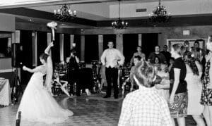 In a reception hall transformed into a lair of elegance by shimmering chandeliers and mood-setting event lighting, the Bride of Brilliance stands poised. Clad in her gown of purity, she surveys the crowd with a determined gaze. With a swift yet graceful motion, she hurls her Floral Fistful—her bouquet—toward the gathered admirers. Among them stands an enigmatic figure, eyes fixed on this radiant heroines ceremonial power play. :The Event Heroes at Black Tie Productions