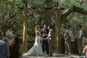 In the heart of natures sanctuary, beneath an archway woven with blossoms, stand two valiant souls—their hands interlocked in a pledge of unity. Encircled by their loyal entourage and witnesses from realms near and far, their union takes center stage amid the tranquil glow of celestial lights. Mighty trees stand sentinel, crafting a majestic tableau against which this epic odyssey unfolds. To seal their bond with a harmony befitting heroes, a maestro from Michigan conjures melodies that dance through the air, completing this enchanting saga for all time. :The Event Heroes at Black Tie Productions