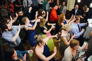 Inside the grand hall, an electrifying group of partygoers assemble, their spirits ignited as they raise their drinks high. With synchronization that defies gravity, they move to the pulsating rhythms unleashed by none other than Sonic Pulse—a legendary wedding DJ from Michigan—whose beats transform mere mortals into a coalition of dance-floor superheroes!. :The Event Heroes at Black Tie Productions