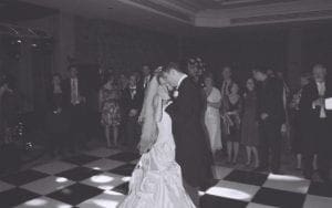 In the glowing radiance of elegant event lighting, two figures glide with unstoppable grace across the checkered battlefield of dance. Onlookers, clad in their ceremonial armors of formal attire, gather around, transfixed by the couples superhuman precision and rhythm. Together, they embody a symphony of motion—a dance that captures both time and hearts—casting a spell upon all who dare to witness this legendary spectacle. :The Event Heroes at Black Tie Productions