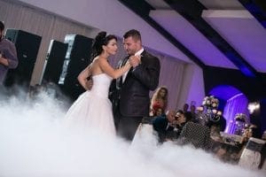 As the scene unfolds in this epic celebration, the bride and groom dazzle with every step, gliding effortlessly across a mist-laden floor that seems to shimmer under their feet. Their love transforms them into graceful heroes of dance, while beams of light slice through the venue like beacons illuminating their shared journey. Guests watch in awe-struck admiration, enraptured by an ambience charged with mystique and wonder. Overseeing this enchanting spectacle is Michigan’s maestro of melodies—the wedding DJ—whose sonic powers elevate the evening to legendary heights!. :The Event Heroes at Black Tie Productions