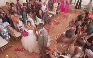 As the radiant couple strides down their aisled path, a hush falls over the grand indoor venue, transformed into a realm of wonder by their mere presence. Guests stand as sentries and sit like guardians, bearing witness to this epic union. Soft beams of ethereal light cascade over the scene, casting a heroic glow that immortalizes every cherished moment in this love-illuminated sanctuary. :The Event Heroes at Black Tie Productions