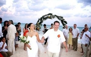 Under the cloak of a muted sky, where clouds gather like silent guardians, the Bride and Groom stride hand in hand, their love igniting the sands beneath them. Behind them stands an elegant arch—a beacon of their unity against natures vast canvas. Gathered nearby are their allies, guests capturing each cherished moment with flashes of brilliance. To further illuminate this extraordinary day, summon a Michigan wedding DJ to weave sonic magic—elevating this spectacle to legendary heights and ensuring that all who attend will remember it forever!. :The Event Heroes at Black Tie Productions