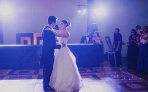 In the grand hall of celebration, where love harnesses its extraordinary power, the dynamic duo stood at the center—Bride and Groom, champions of unity. As they embarked on their first dance upon a timeless wooden floor, they were encircled by an assembly of supportive allies. Above them, Black Tie Productions wielded their mighty illumination skills, casting a mystical glow with elegant purple lights. This transformed the setting into an enchanting realm where magic dwelled in every shadow and corner. Together, surrounded by admiration and wonderment, Bride and Groom unleashed the force of love in a spectacular display!. :The Event Heroes at Black Tie Productions