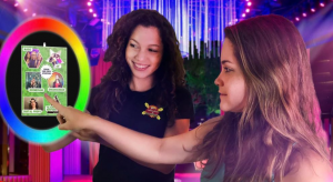 In a world where technology and style converge, two formidable women don their alter egos as digital heroines. They command attention as they engage with a mesmerizing circular touchscreen display, alive with vibrant images and pulsating energy. The atmosphere around them is electrified by vibrant event lighting and adorned with elegant decorations, transforming the scene into an epic stronghold worthy of Black Tie Productions finest gala. :The Event Heroes at Black Tie Productions