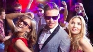 In the heart of the electrifying event, a suited figure emerges—a man of mystery and charisma, his sunglasses gleaming under the vibrant lights. Beside him, two dazzling heroines in chic gowns and shades wield their own brand of magic. Together, they own the stage with dynamic grace and style. This is no mere gathering; its a masterclass in celebration brought to life by none other than the Event Heroes, transforming every night into an unforgettable adventure!. :The Event Heroes at Black Tie Productions