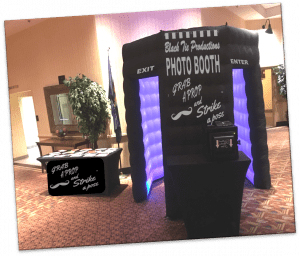 In the heart of the celebration universe, emerges the formidable inflatable photo booth, emblazoned with the mighty emblem of Black Tie Productions. To its left, a legendary cache of props awaits—each a tool for transformation and adventure. A bold sign commands: Grab a Prop and Strike a Pose, inviting all heroes to unleash their inner star. Designed with precision and safety in mind, the booth features clearly marked entrances and exits, standing as an impeccable choice for any epic gathering that demands memories be captured in style!. :The Event Heroes at Black Tie Productions