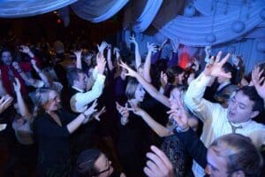 Underneath a canopy of electrifying blue light and ethereal white drapery, the crowd vibrates with energy. Joy radiates from vibrant smiles and raised arms, fueled by the epic atmosphere crafted by the legendary Black Tie Productions. Their expertise in event lighting transforms an ordinary party into an extraordinary spectacle that even superheroes would envy!. :The Event Heroes at Black Tie Productions