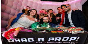 In the heart of a vibrant gathering, heroes draped in dazzling capes of color assembled near the legendary Grab a Prop! station. Armed with quirky glasses and extravagant boas as their mighty accessories, they stood united around the photo booth—a shimmering fortress of fun—illuminated by the unparalleled brilliance conjured by Event Heroes masterful spectacle skills. :The Event Heroes at Black Tie Productions