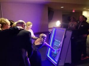 In the midst of a bustling gala, where elegance danced with excitement, a league of finely-attired guests gathered around a majestic vertical beacon—a mirror aglow with vibrant tales. This gleaming wonder was none other than the creation of Event Heroes, guardians of style and enchantment. With their premium photo booth powers, they elevated the ambiance to new heights of sophistication and grace, their presence an undeniable force for good amidst the festive crowd. :The Event Heroes at Black Tie Productions