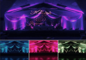 Behold the grand stage, a bastion of style and elegance, cloaked in majestic drapes and a floral fortress that captivates the senses! Bathed in the radiant hues of purple, teal, and pink luminescence, this sanctuary of light transforms into a beacon of celebration. From all corners, three snapshots capture the electric ambiance as it dances with life—a setting worthy of Michigan’s mightiest wedding DJs or photo booth heroes to unleash their powers within!. :The Event Heroes at Black Tie Productions