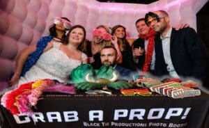 In the bustling heart of celebration city, a dynamic assemblage of revelers circles the Photo Booth Lair, gleaming with vibrant props and a bold Snag Your Super Prop! emblem. The arsenal of flamboyant accessories beckons heroes and heroines alike to leap into action-packed photo fun. Whether its a titanic festival or an intimate gathering, Event Heroes stand poised to unleash spectacular memories in a flash—because every party needs its heroic moments!. :The Event Heroes at Black Tie Productions