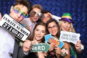 In a dazzling display of charisma and color, a spirited assembly, armed with playful props and wielding signs emblazoned with messages that evoke laughter, strikes a pose before the vast canvas of blue. This dynamic tableau is brought to life by none other than Black Tie Productions—the maestros of luminescent spectacle and champions of exuberant ambiance. With unmatched prowess, they transform ordinary moments into epic tales bathed in light and vibrancy!. :The Event Heroes at Black Tie Productions