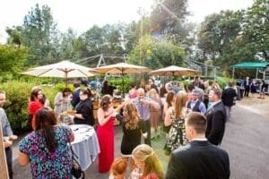 In a vibrant oasis of emerald splendor, a band of joyful revelers assembles for an epic outdoor gathering. Tables and umbrellas stand sentry, offering shade and comfort as the heroes of the event forge unforgettable memories. With the legendary photo booth rental from Black Tie Productions at their side, they seize each moment in electrifying snapshots. This paradise provides the perfect backdrop for these champions to unwind and connect with flair and panache!. :The Event Heroes at Black Tie Productions