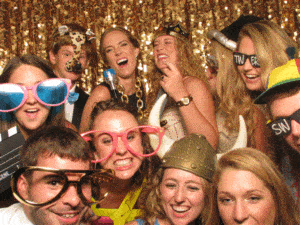 In a dazzling display of fun and festivity, a dynamic team clad in vibrant, playful costumes and oversized, whimsical glasses assembles boldly before a shimmering gold sequin backdrop. With smiles that light up the universe, they embody the triumphant spirit of joy and excitement unleashed by the legendary Event Heroes at your celebration. :The Event Heroes at Black Tie Productions